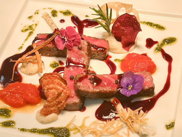 彩り豊かな野菜とソースを添えたフレンチの肉料理