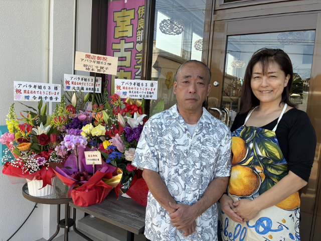 店舗前でお客様を迎えるシェフとソムリエの夫婦